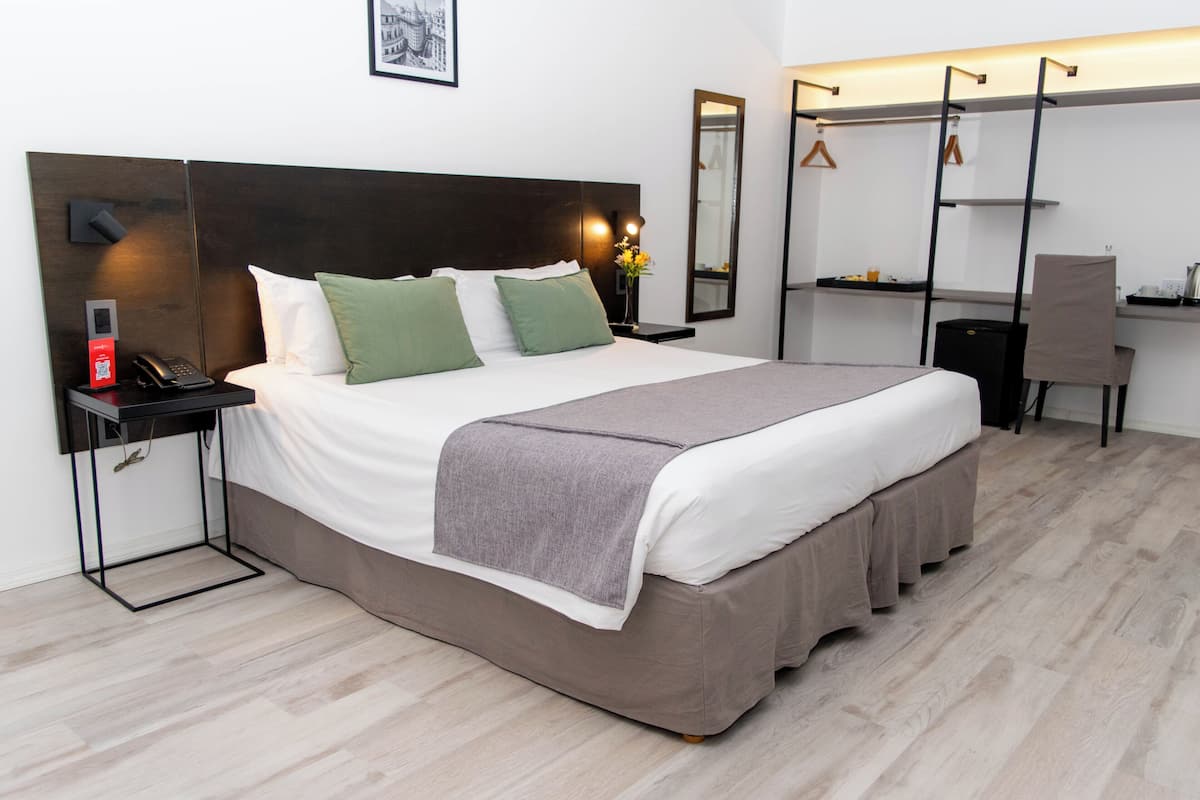 Une chambre d’hôtel moderne avec un grand lit, des tables de chevet, un bureau et une chaise.