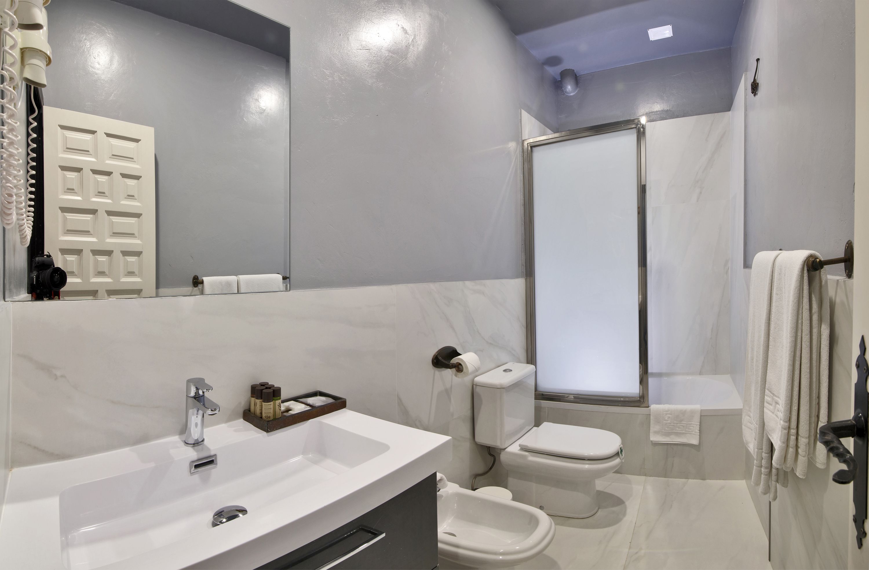 A modern bathroom with a white sink, toilet, and shower.