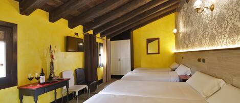 A room with two beds, a wooden ceiling, a desk with a chair, and a mirror on the wall.