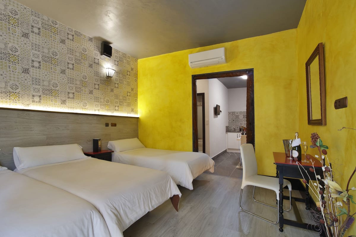 Een hotelkamer met twee bedden, een bureau met stoel, een spiegel en een airconditioning.