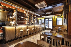 Eine Bar mit einer langen Theke, Hockern und einem gemusterten Boden.