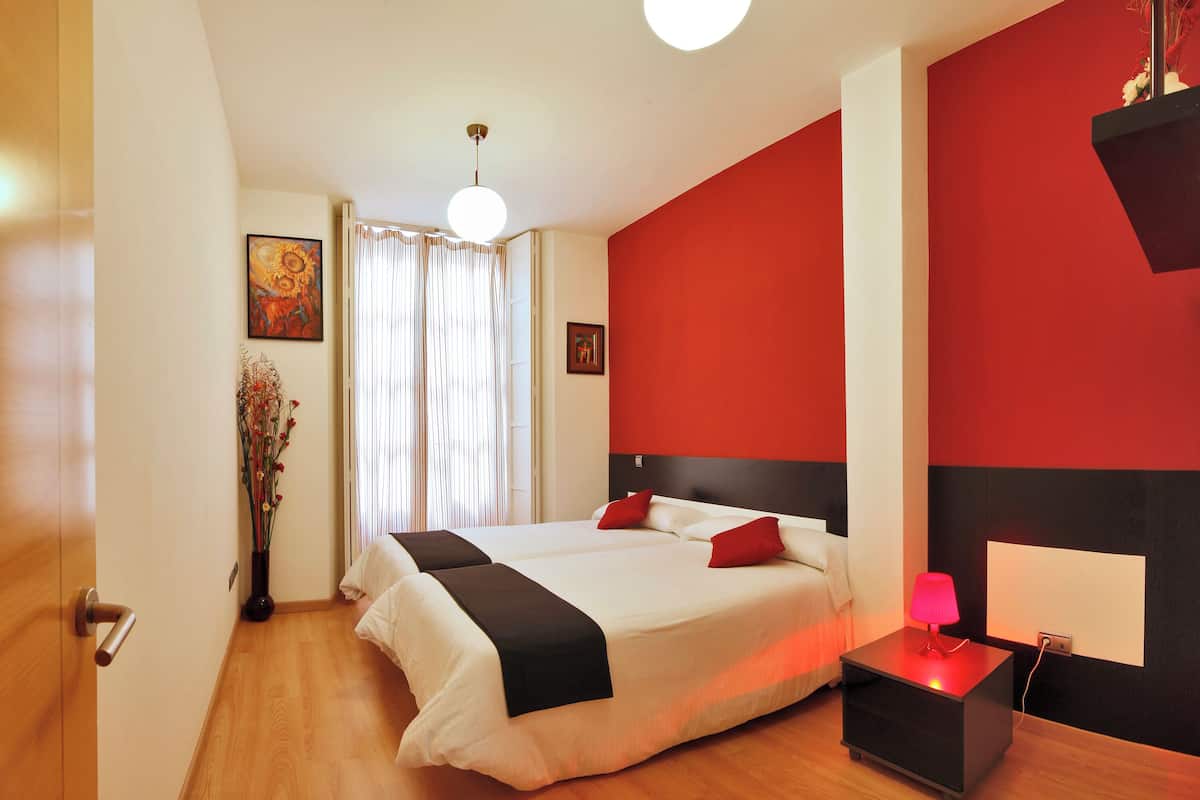 Een moderne hotelkamer met een groot bed, een nachtkastje met een lamp en een rode accentmuur.