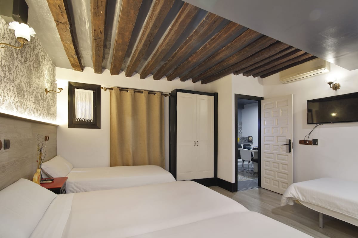 Een kamer met twee bedden, een houten plafond, een aan de muur bevestigde televisie en een deur naar een andere kamer.