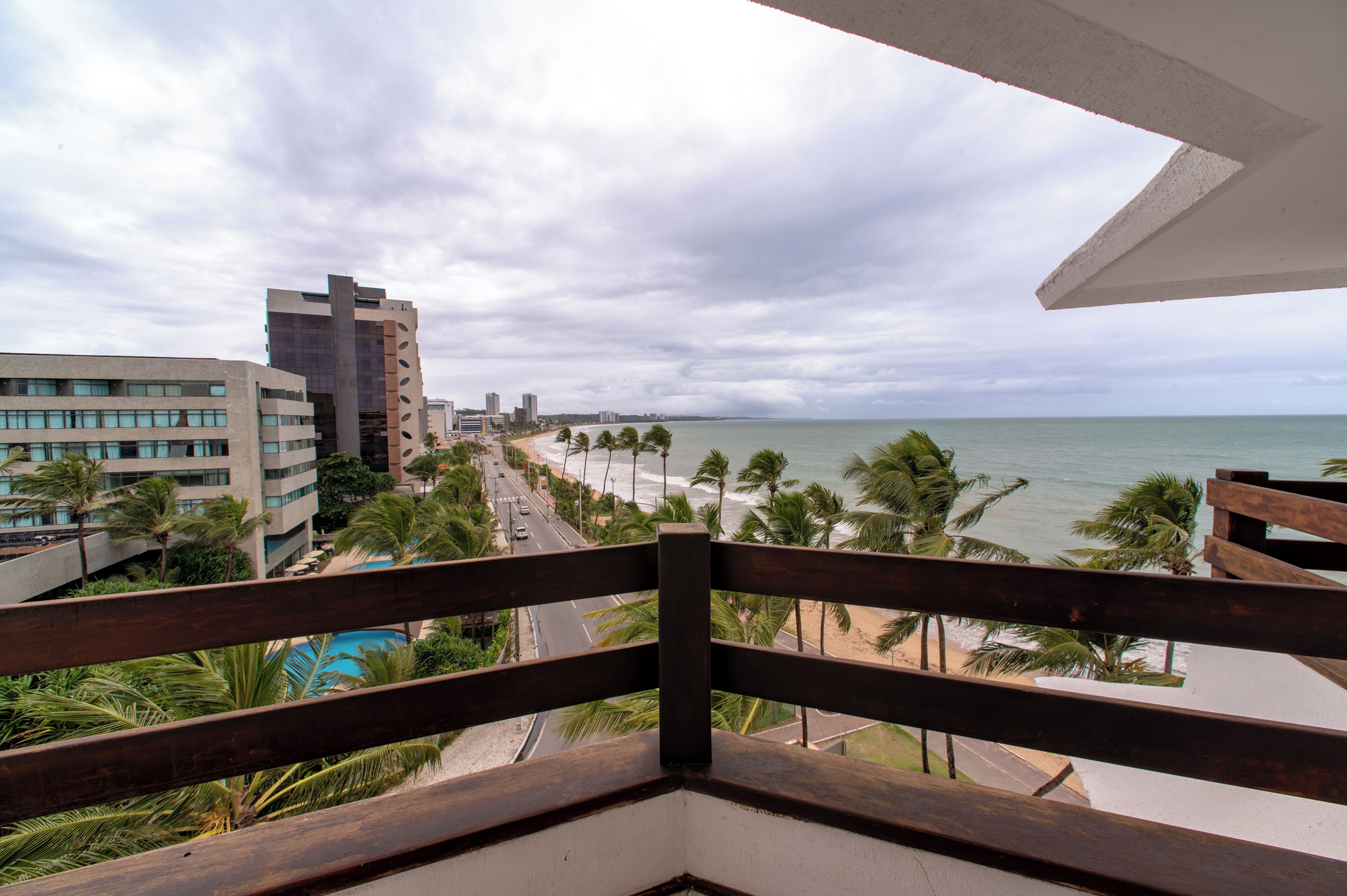 Un balcon avec vue sur une plage, des palmiers et des bâtiments.