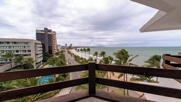 Un balcon avec vue sur une plage, des palmiers et des bâtiments.