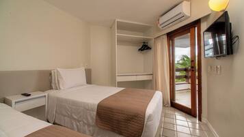 A hotel room with two beds, a wardrobe, a TV, and an air conditioning unit.