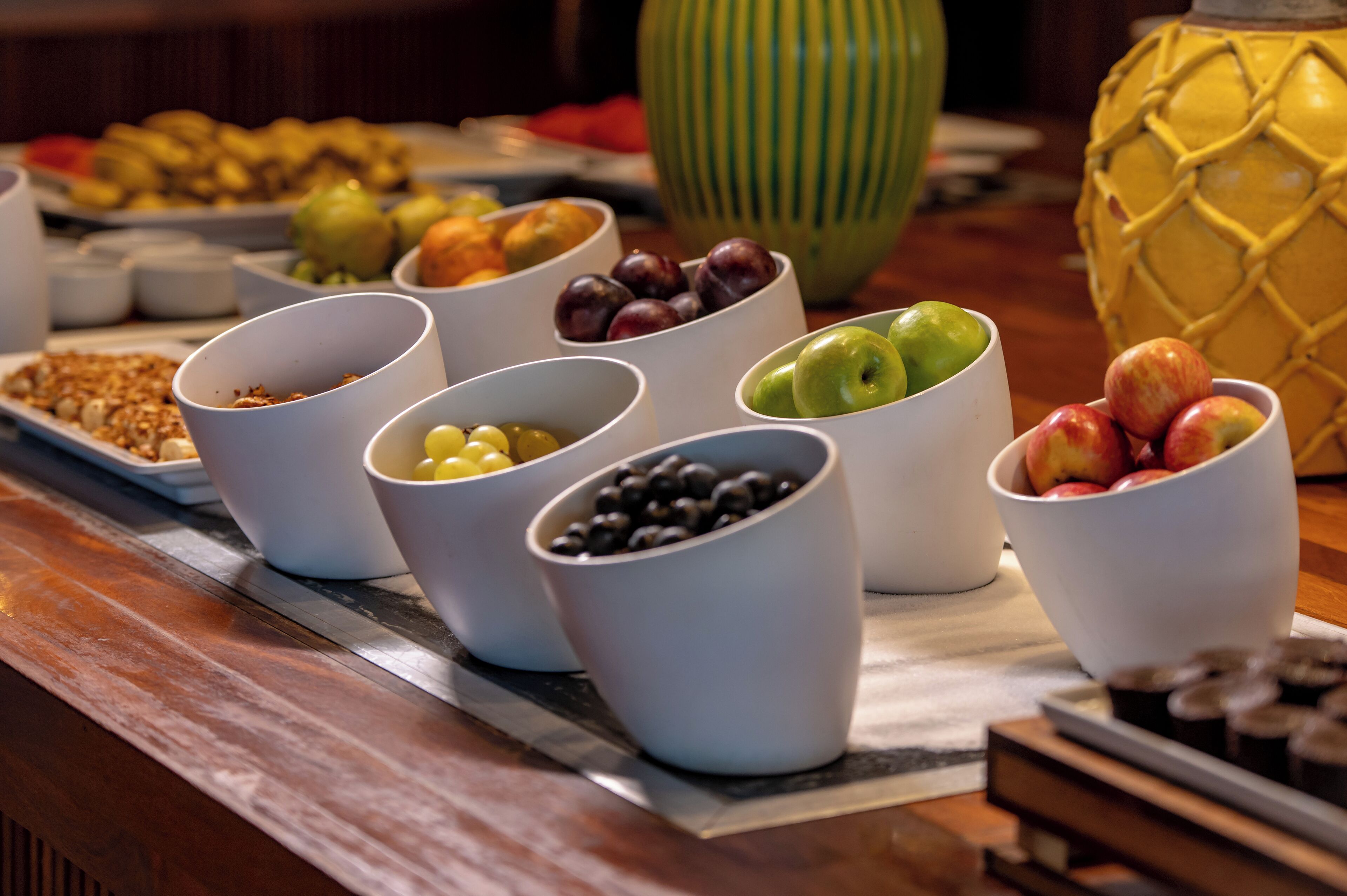 Une table de buffet avec différents plats présentés dans des bols, notamment des fruits et des noix.