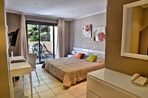 A bedroom with a bed, a desk, a chair, a phone, and a sliding glass door leading to an outdoor area. - Hôtel Des Deux Sorru (Poggiolo)