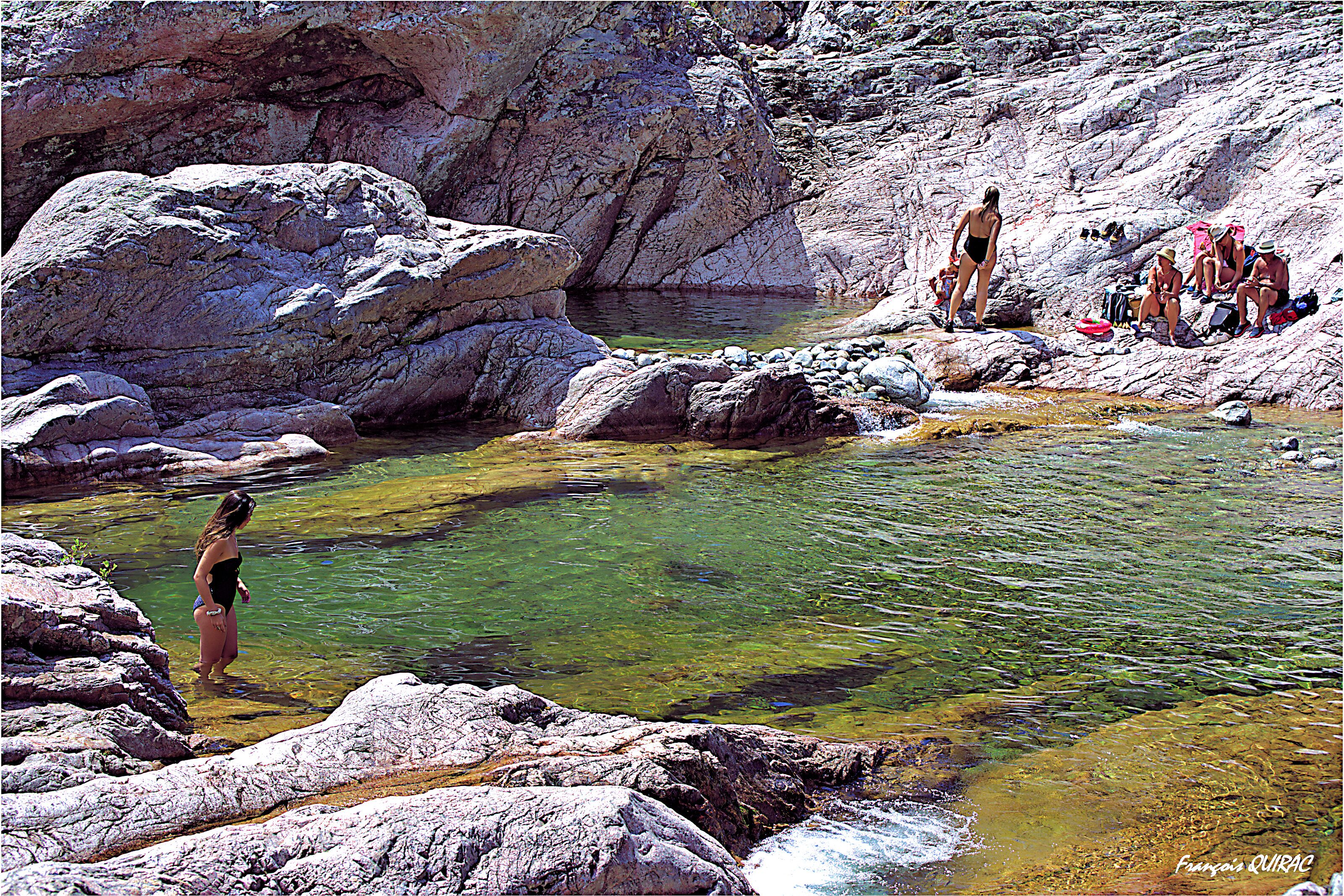 Ein felsiges Becken mit klarem Wasser, umgeben von großen Felsen.