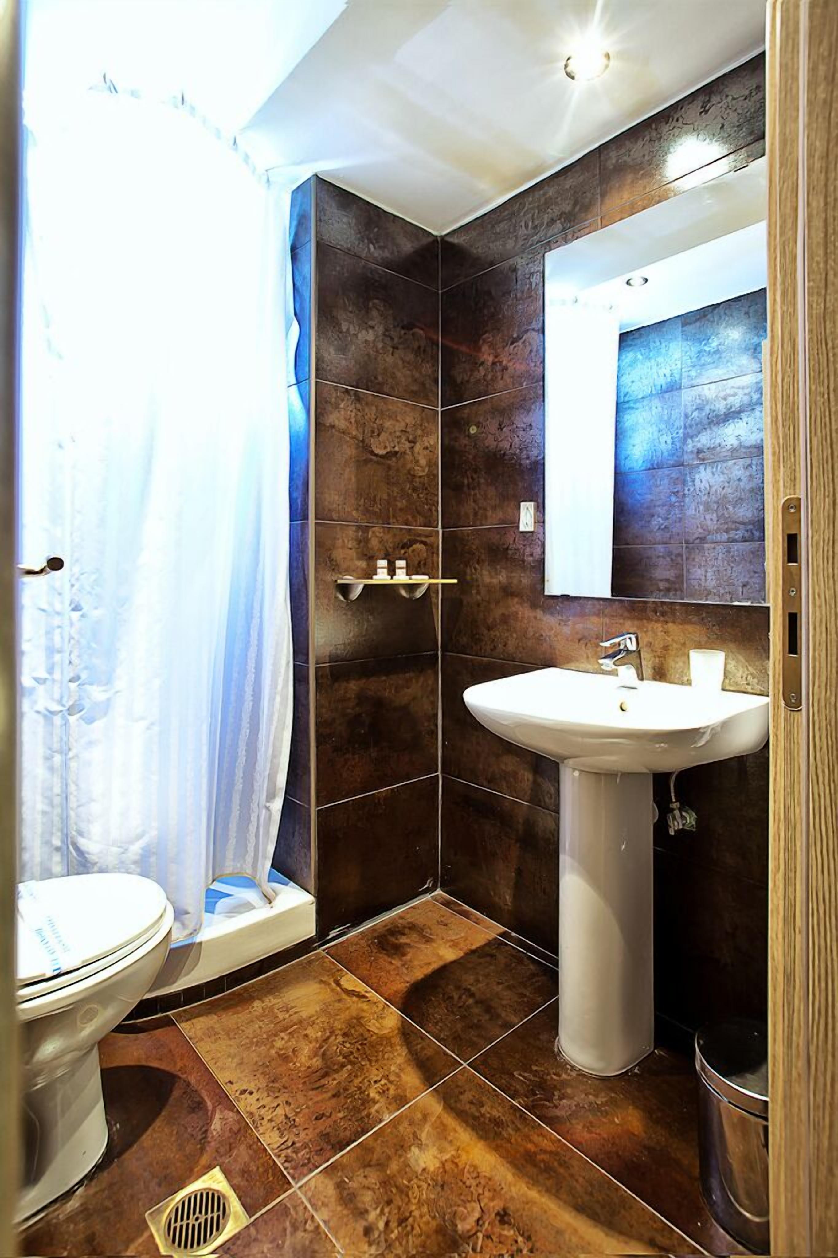 Et badeværelse med toilet, vask og bruseområde.