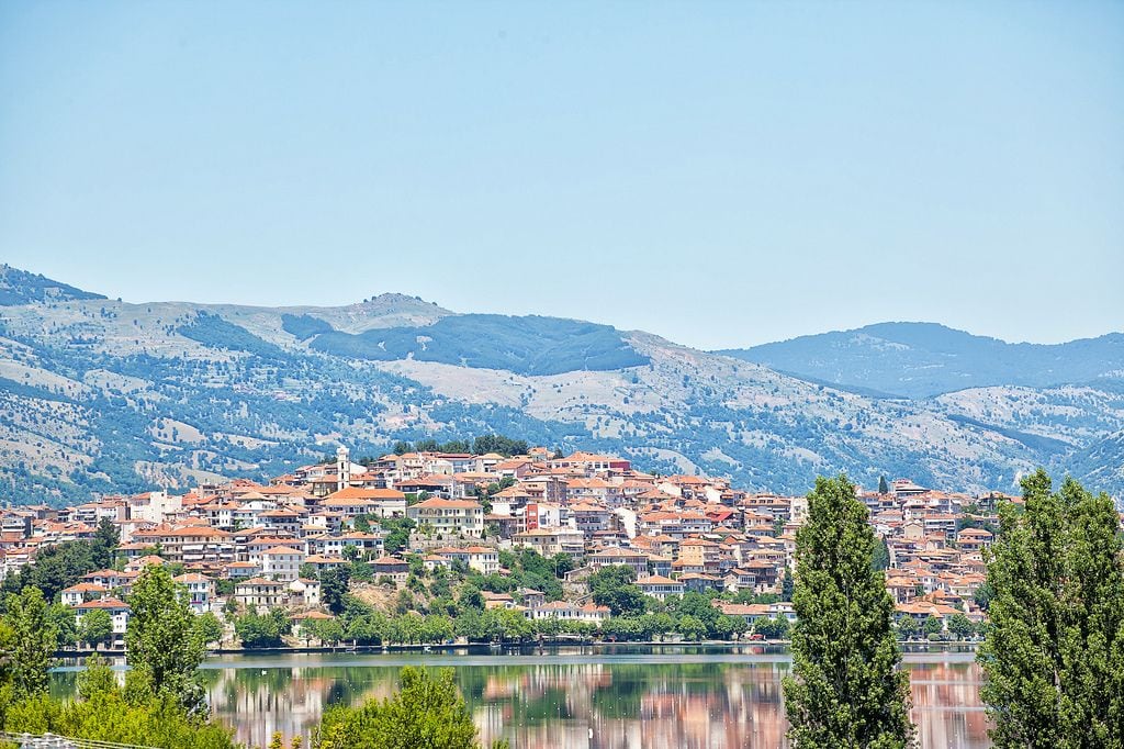 A town with buildings on a hillside overlooking a lake.