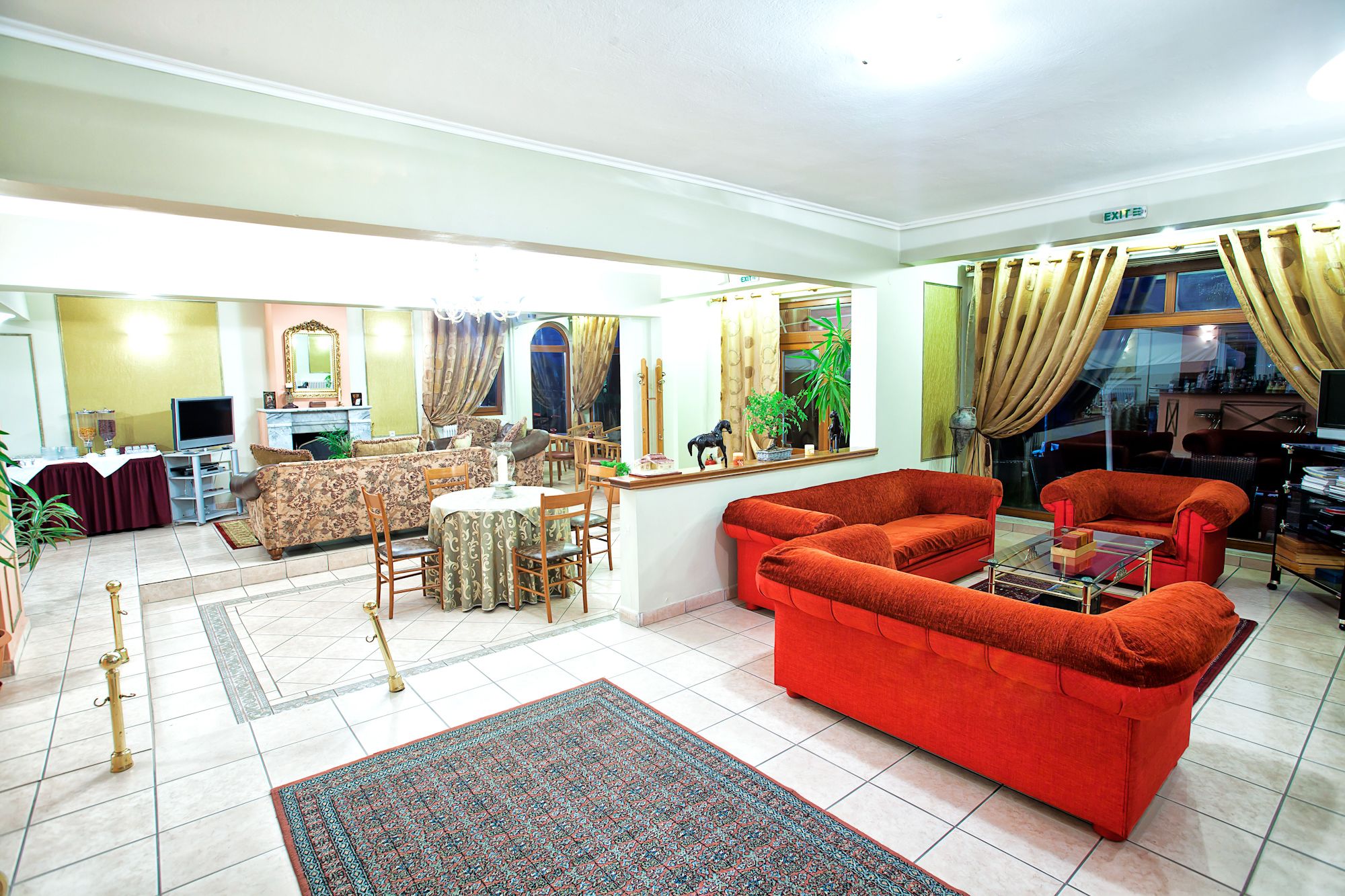 A spacious living room with a red sofa set, a dining area with a table and chairs, and a television.