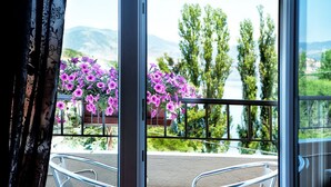 Un balcó amb baranes de metall, vista d'un llac i flors morades.