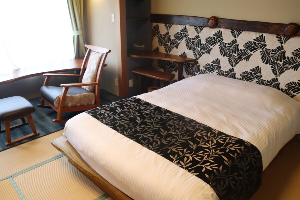 A room with a bed, a chair, a small table, and a shelf.
