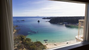 A coastal view from a window, including clear blue sea, sandy beach, and rocky cliffs. - Shimoda View Hotel (Shimoda)
