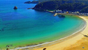 A coastal beach with clear turquoise waters, a sandy shore, and a small pier. - Shimoda View Hotel (Shimoda)