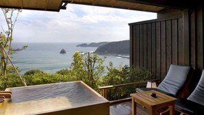 A wooden deck with a hot tub, seating area, and a view of the ocean. - Shimoda View Hotel (Shimoda)