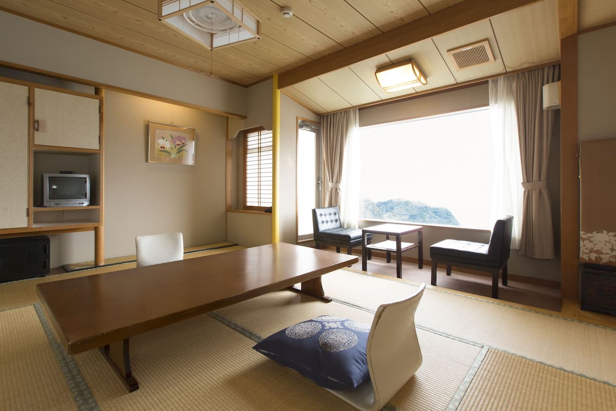 Una habitación japonesa tradicional con suelo de tatami, una mesa de madera baja y disposición de asientos.