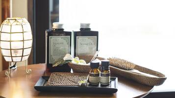 A tray with essential oils, a candle, and a woven basket on a wooden table.