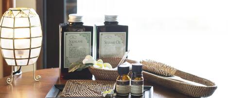 A tray with essential oils, a candle, and a woven basket on a wooden table.