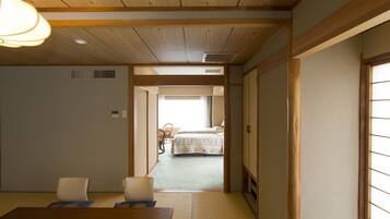 A traditional Japanese room with tatami flooring, a wooden table, and a bed with a patterned bedspread.