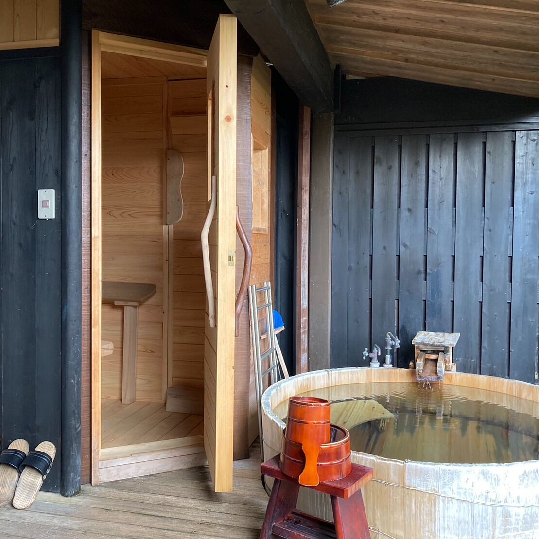 A wooden cabin with a sauna, a wooden bench, and a hot tub.
