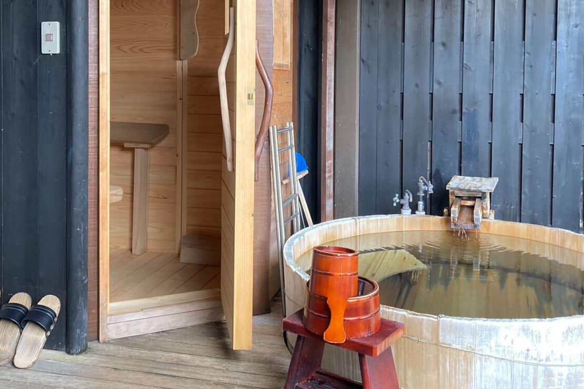 Una cabaña de madera con sauna, banco de madera y bañera de hidromasaje.