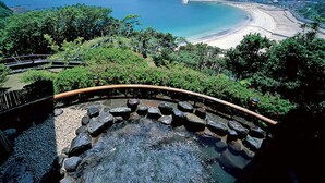 A hot spring surrounded by lush greenery and a beach in the background. - Shimoda View Hotel (Shimoda)