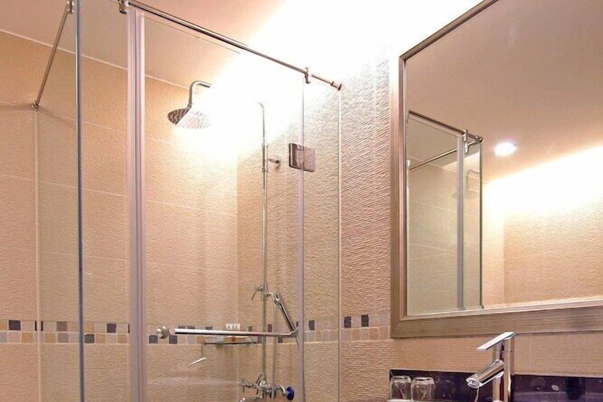 A modern bathroom with a glass shower enclosure, a white sink, and a large mirror.