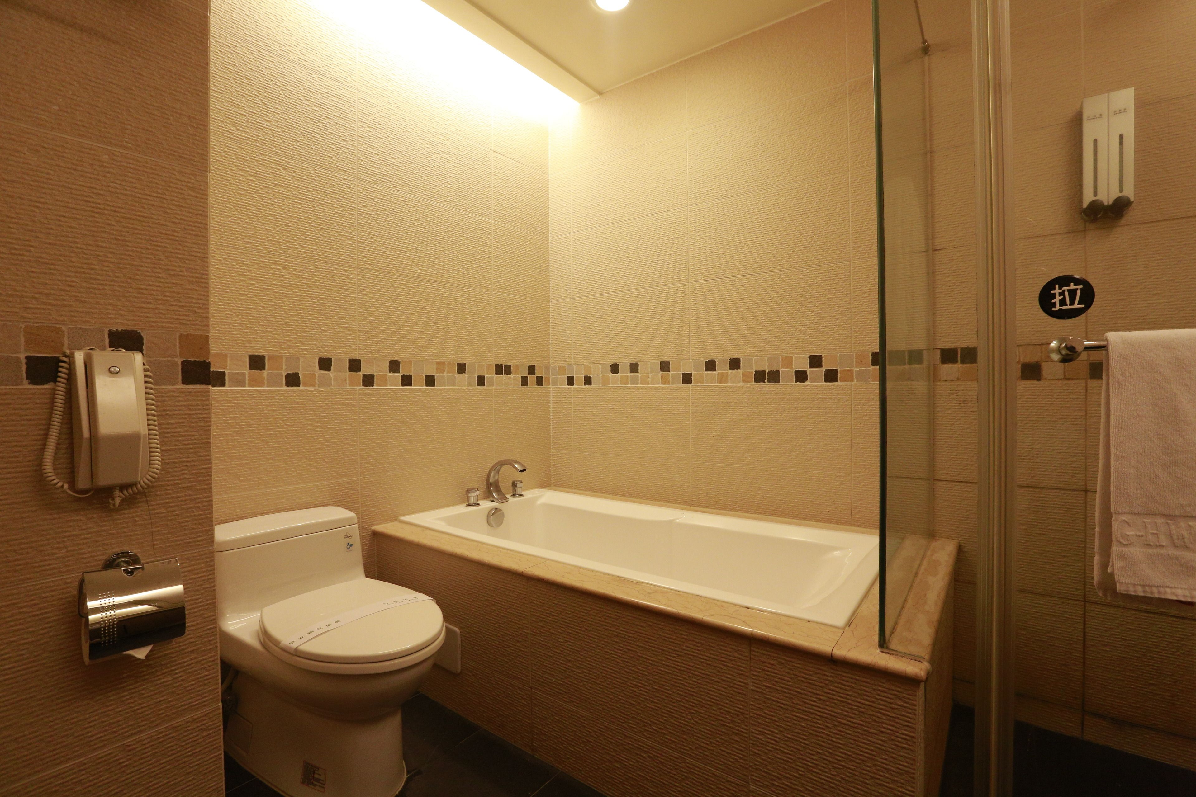 Et badeværelse med toilet, badekar og brusekabine i glas.