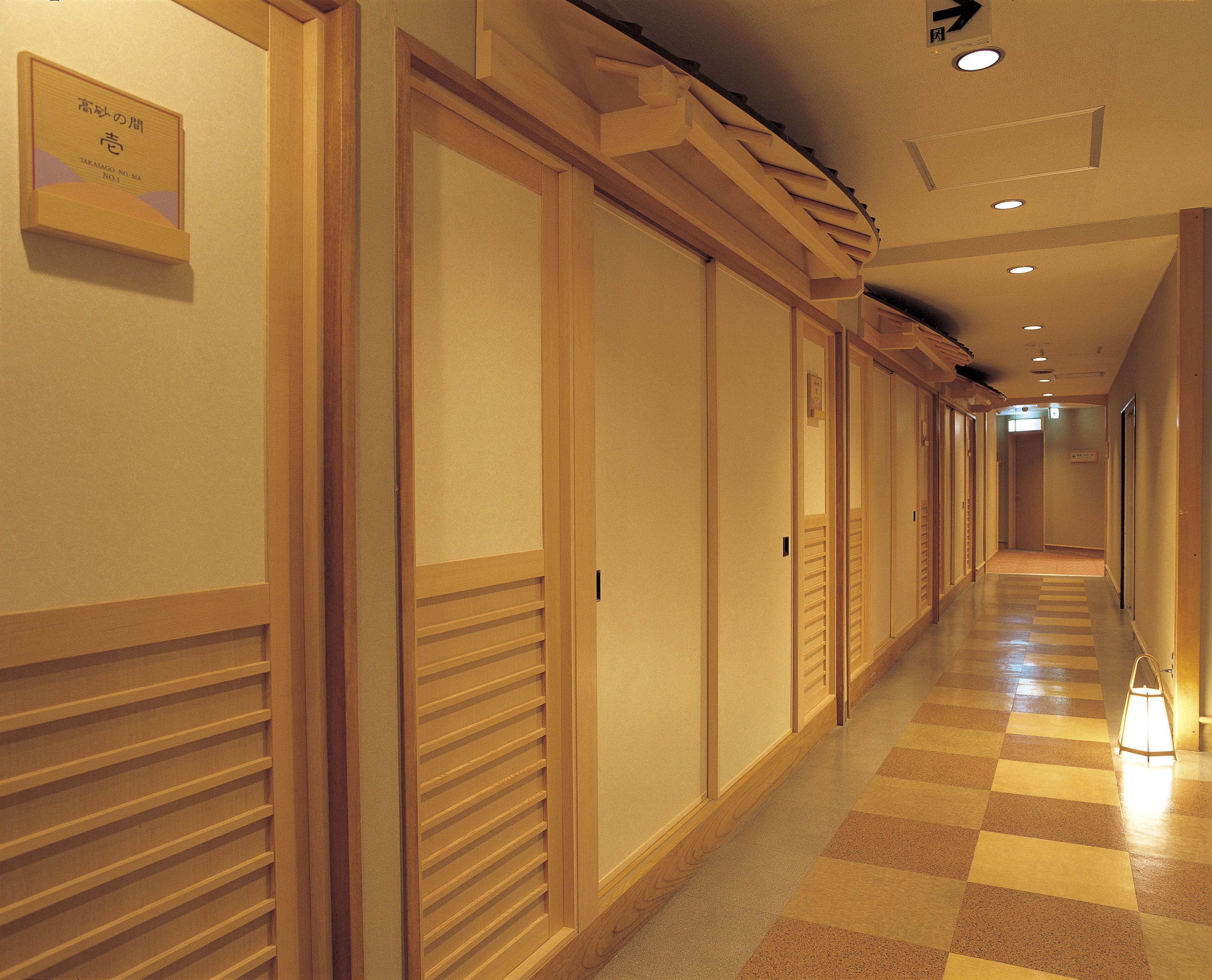 A hotel corridor with wooden doors, a checkered floor, and a sign on the wall.