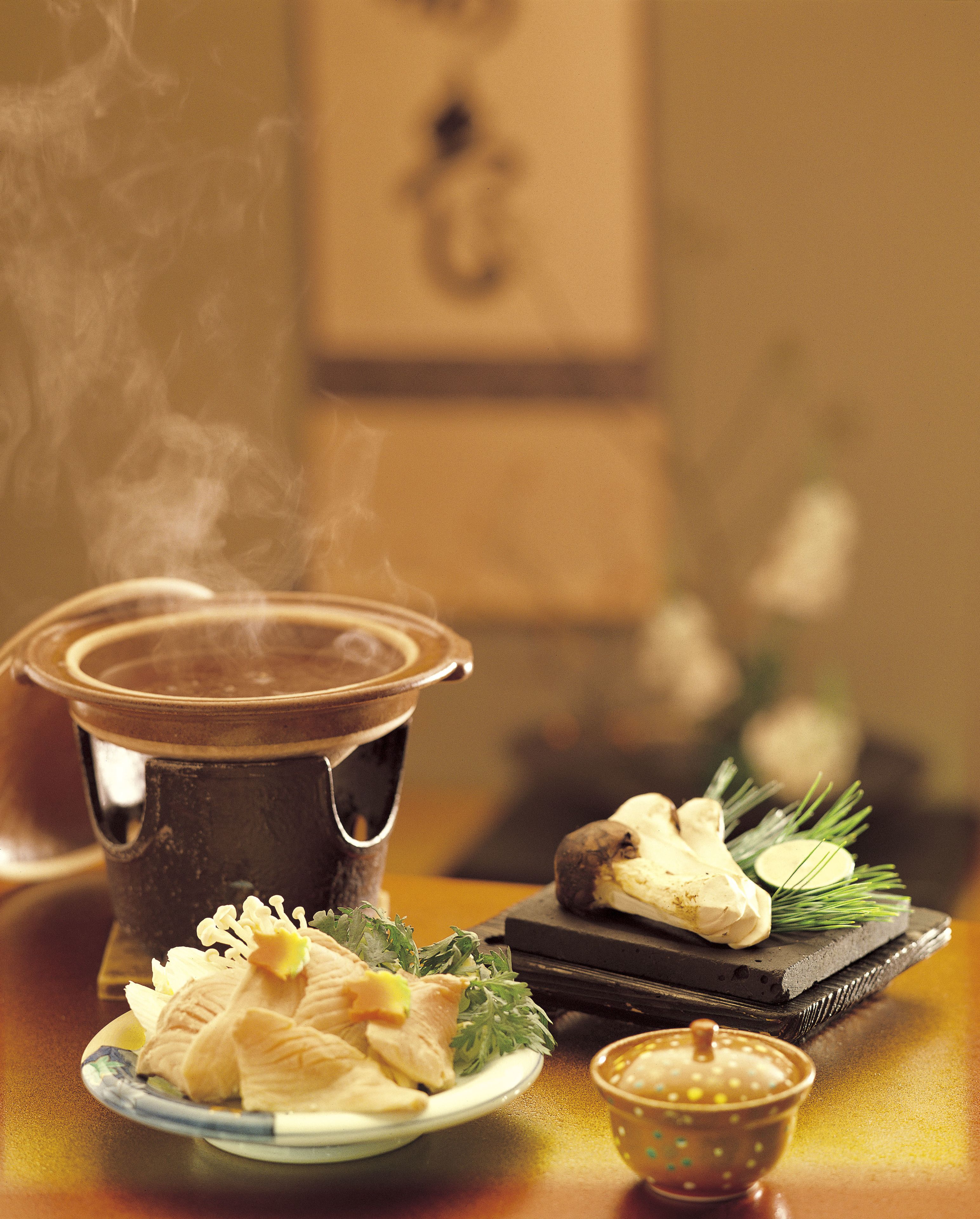 A traditional Japanese hot pot setup with a pot, a plate of food, and a small bowl.