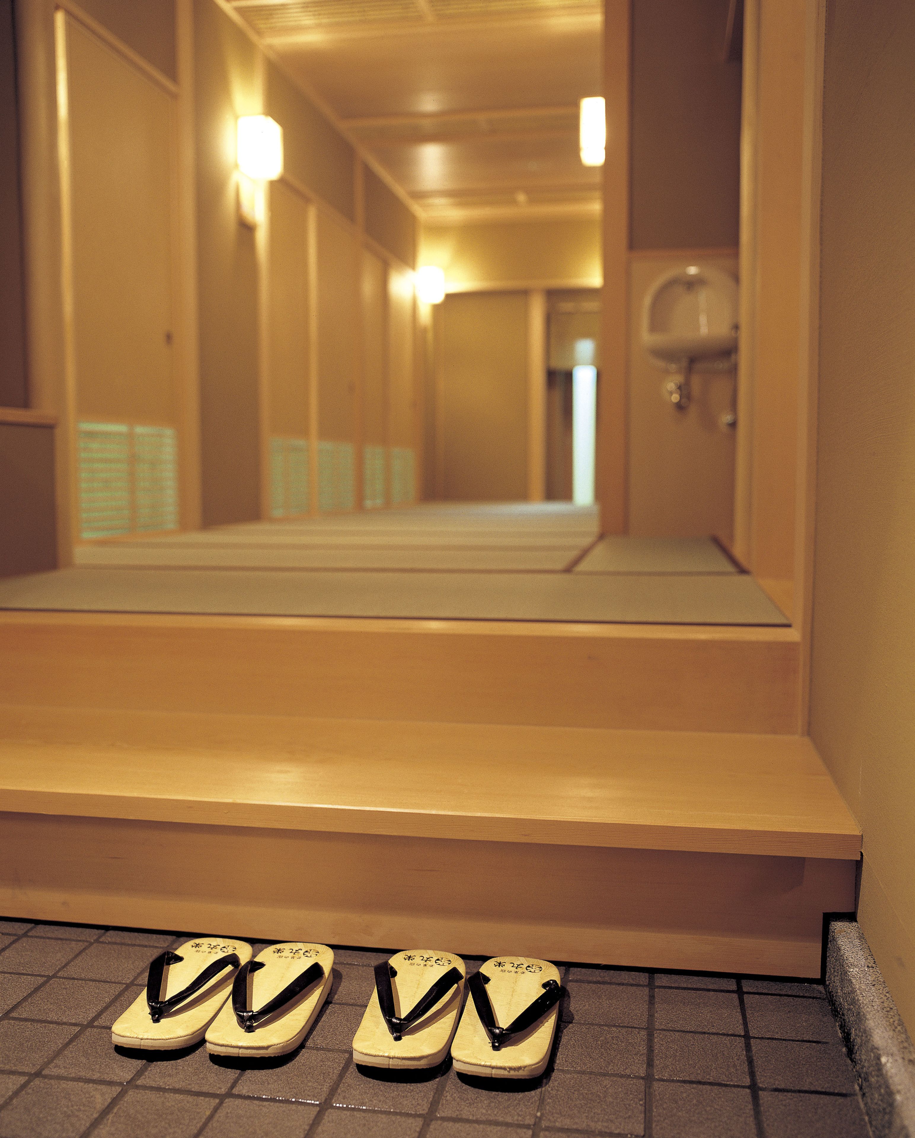 Un couloir avec des marches menant à un miroir, et une paire de tongs posée sur le sol.