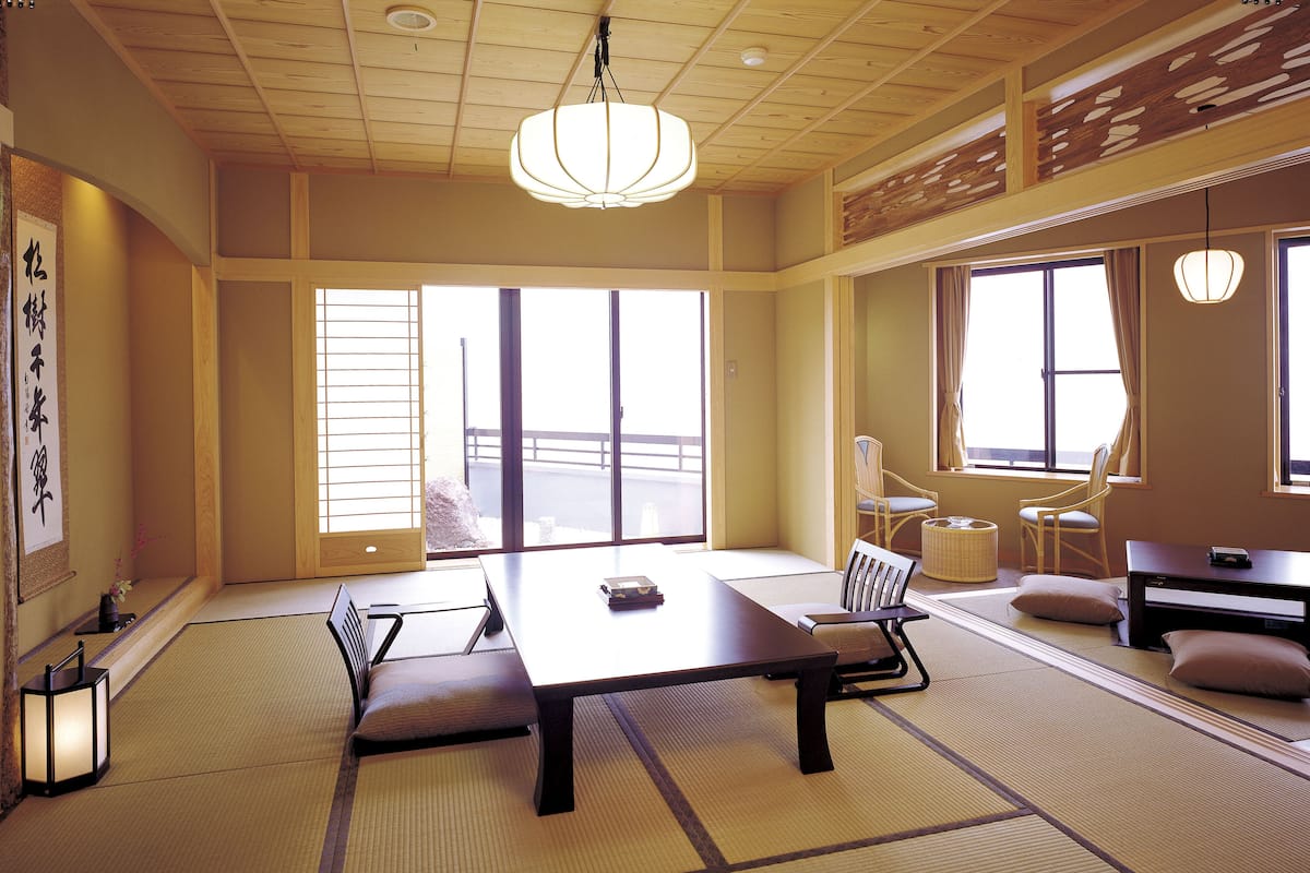 A traditional Japanese room with tatami flooring, a low table, and chairs.