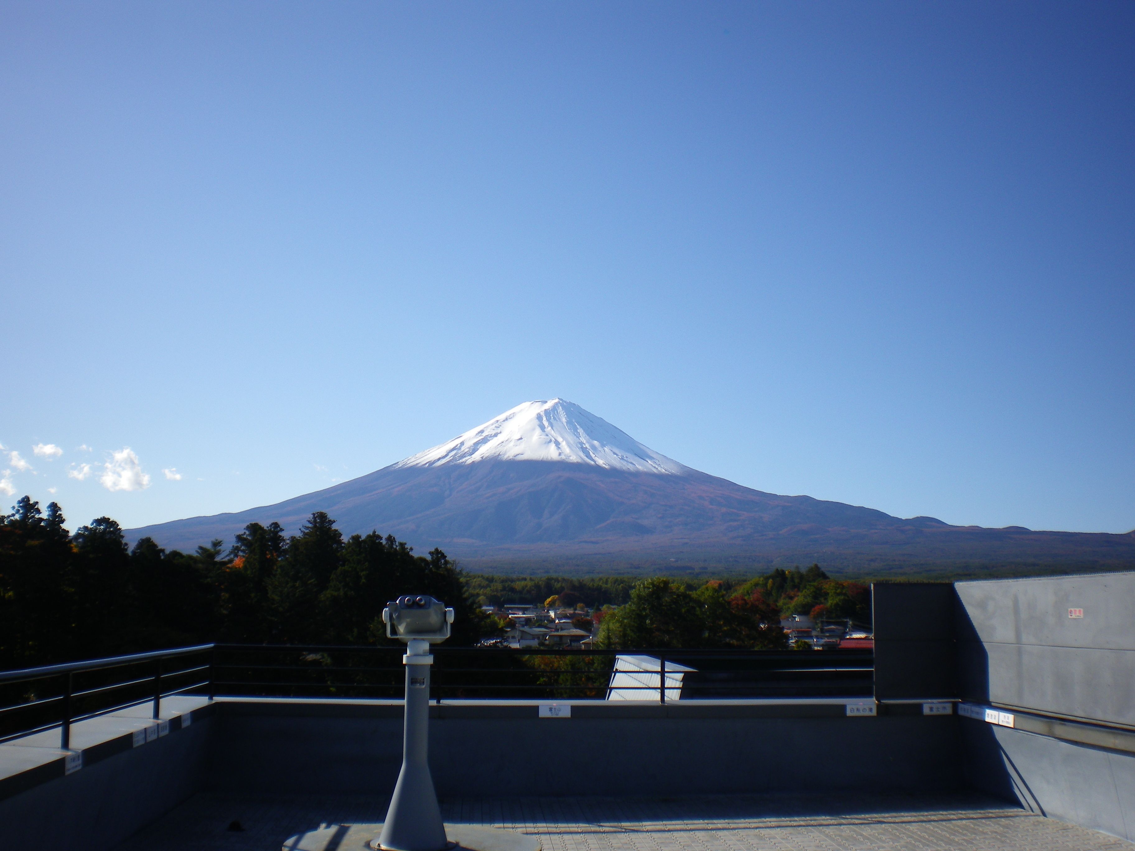 Vue du mont Fuji depuis une terrasse sur le toit, avec un télescope au premier plan.