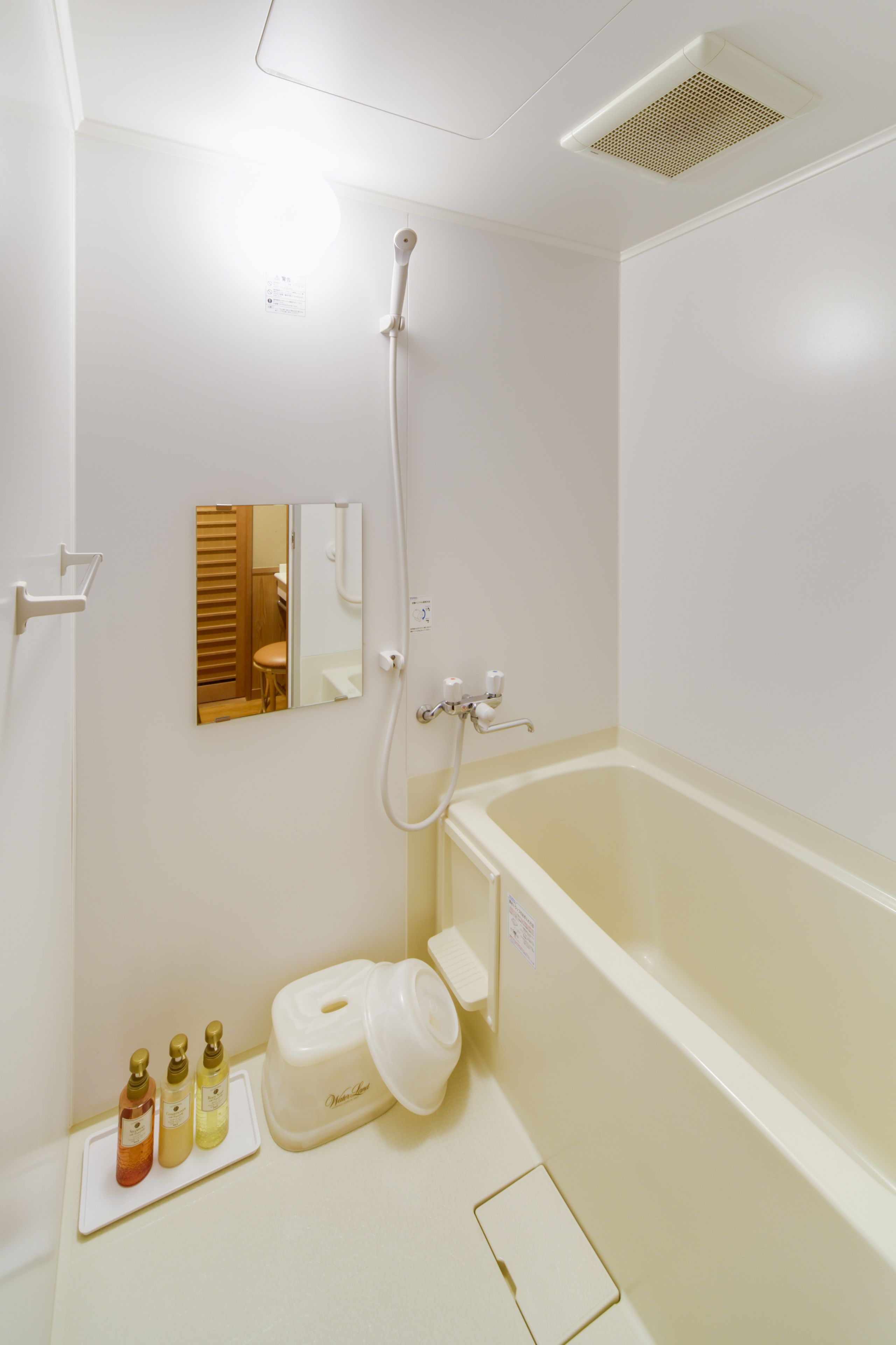 A bathroom with a bathtub, a shower, a mirror, and toiletries on the counter.