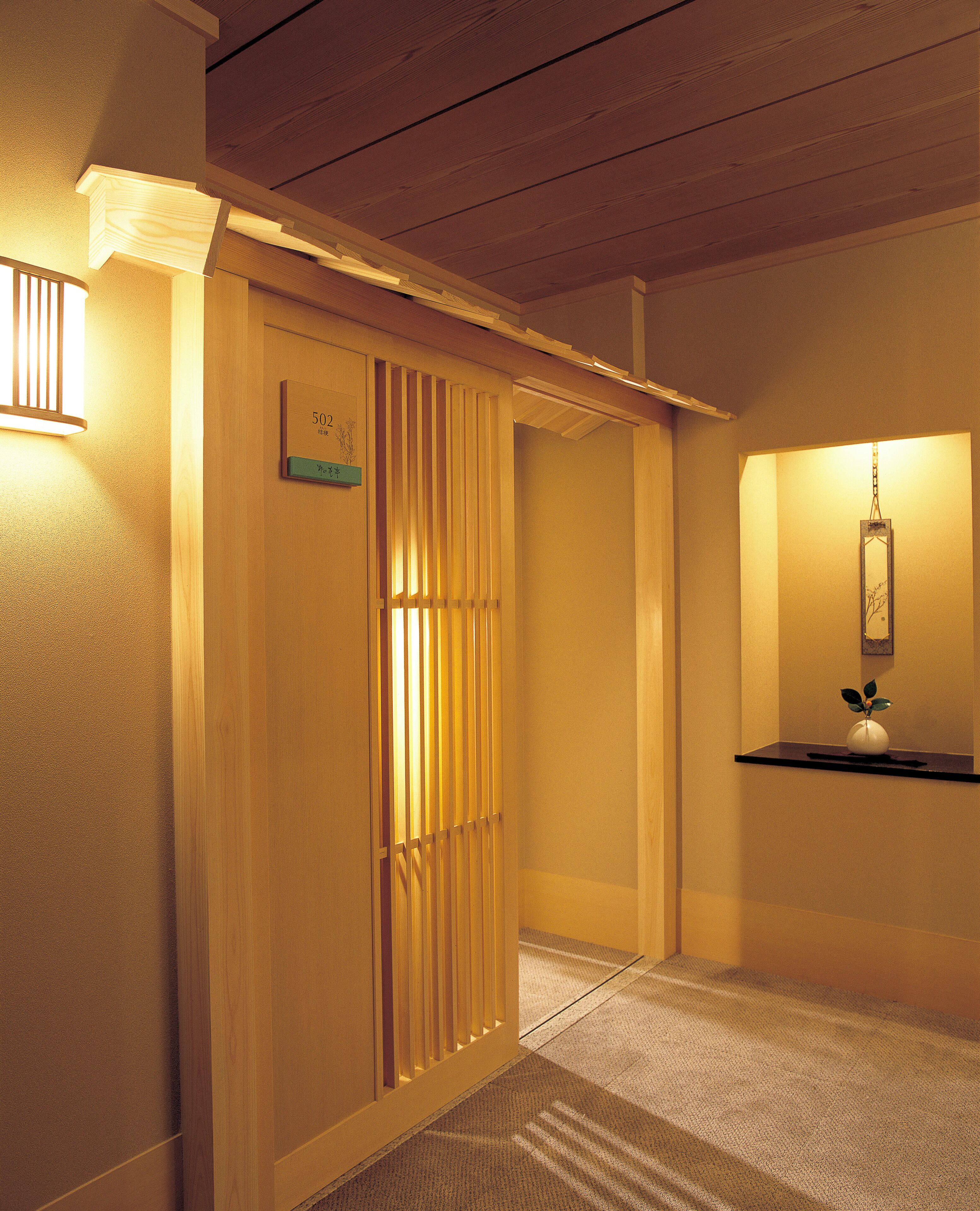 Um corredor de hotel com painéis de madeira, um balcão de recepção e um lustre.