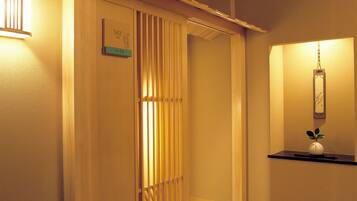 Um corredor de hotel com painéis de madeira, um balcão de recepção e um lustre.