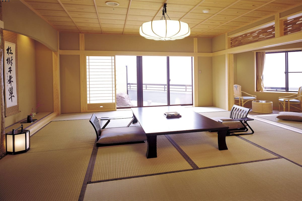 A traditional Japanese room with tatami flooring, a low table, and sliding doors.