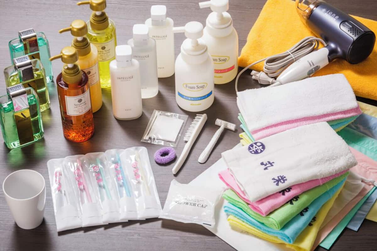 A variety of toiletries and personal care items, including bottles of shampoo, soap, and a hairdryer, arranged on a wooden surface.