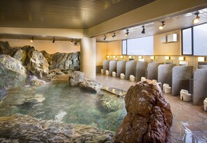 A hot spring bath area with stone walls, a clear pool, and multiple seating areas with lamps. - Wakakusa no Yado Maruei Ryokan (Fujikawaguchiko)