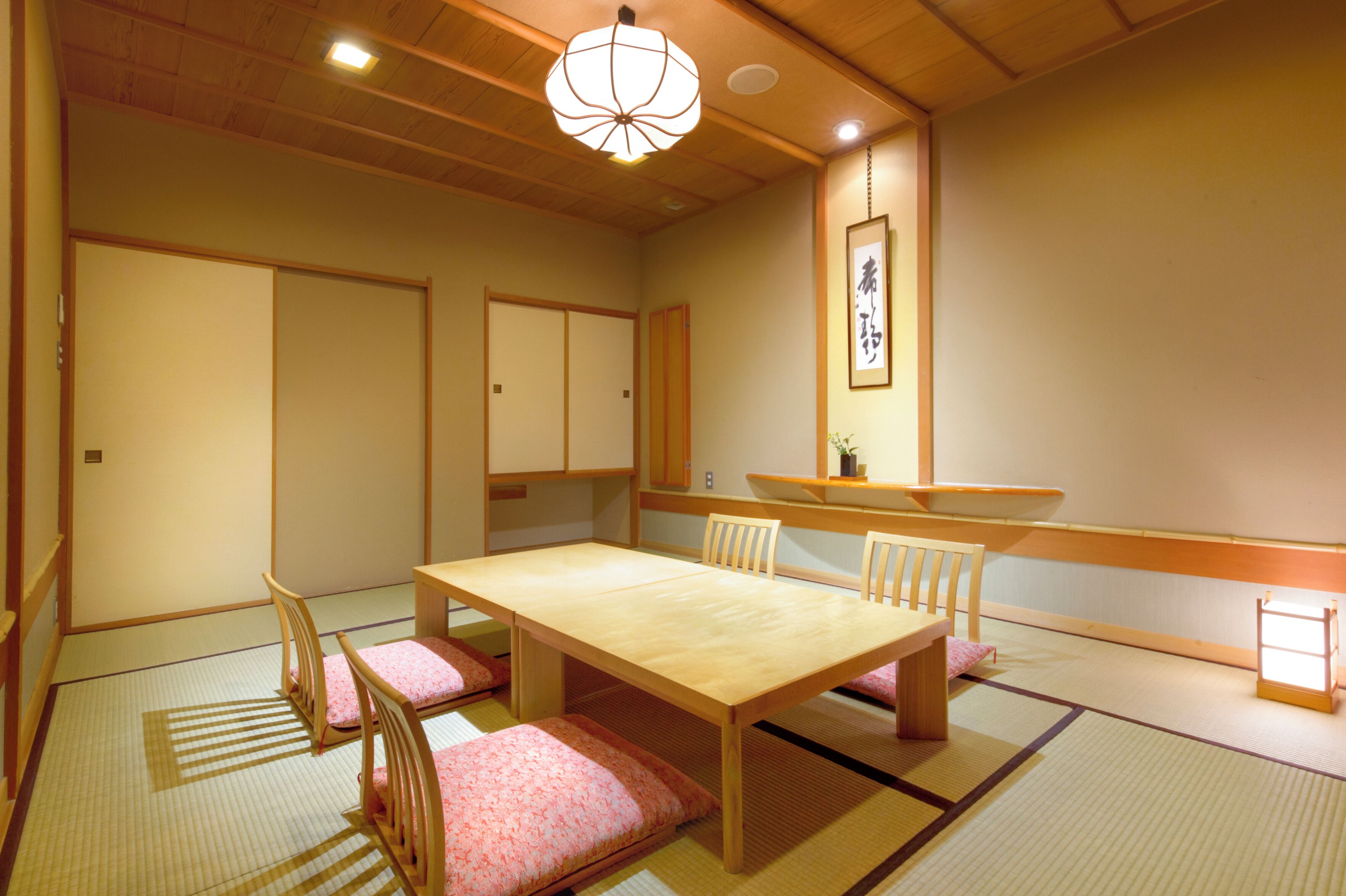 A traditional Japanese room with tatami flooring, a low wooden table, and matching chairs.