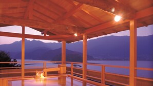 A wooden deck with a view of mountains and a body of water. - Wakakusa no Yado Maruei Ryokan (Fujikawaguchiko)