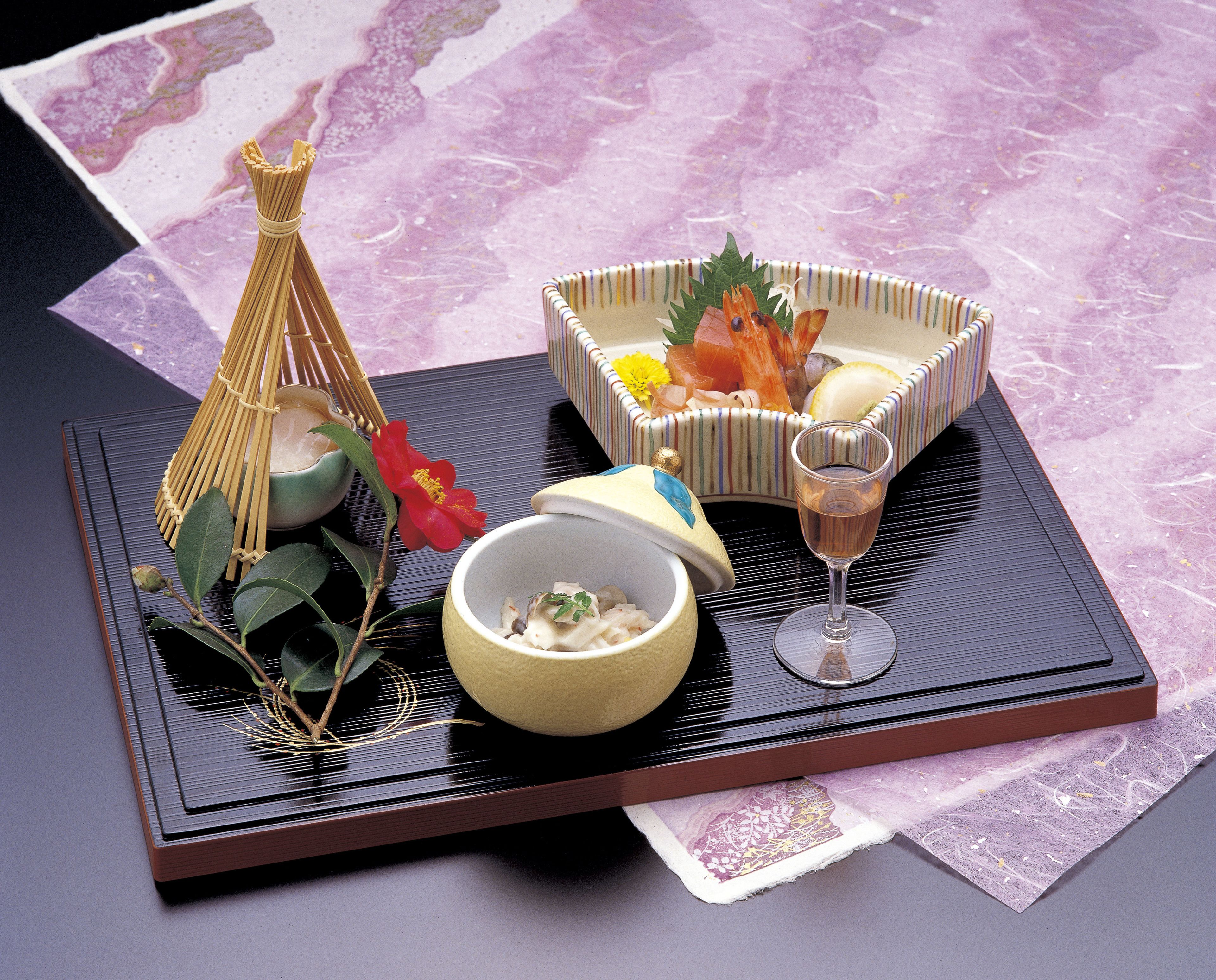 A tray with food items, a glass of wine, and a decorative item on a table.