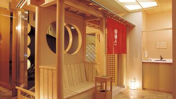Una habitación tradicional japonesa con suelo de tatami, una cama de madera con dosel y un lavamanos pequeño.