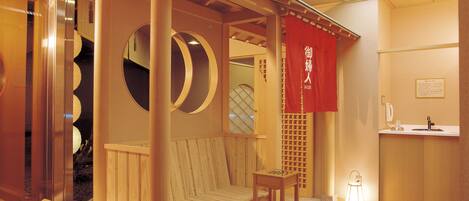 A traditional Japanese-style room with a tatami mat floor, a wooden bed with a canopy, and a small washbasin.