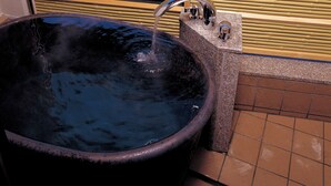 A large black bathtub with a faucet, a wooden fence, and a view of a lake and mountains. - Wakakusa no Yado Maruei Ryokan (Fujikawaguchiko)
