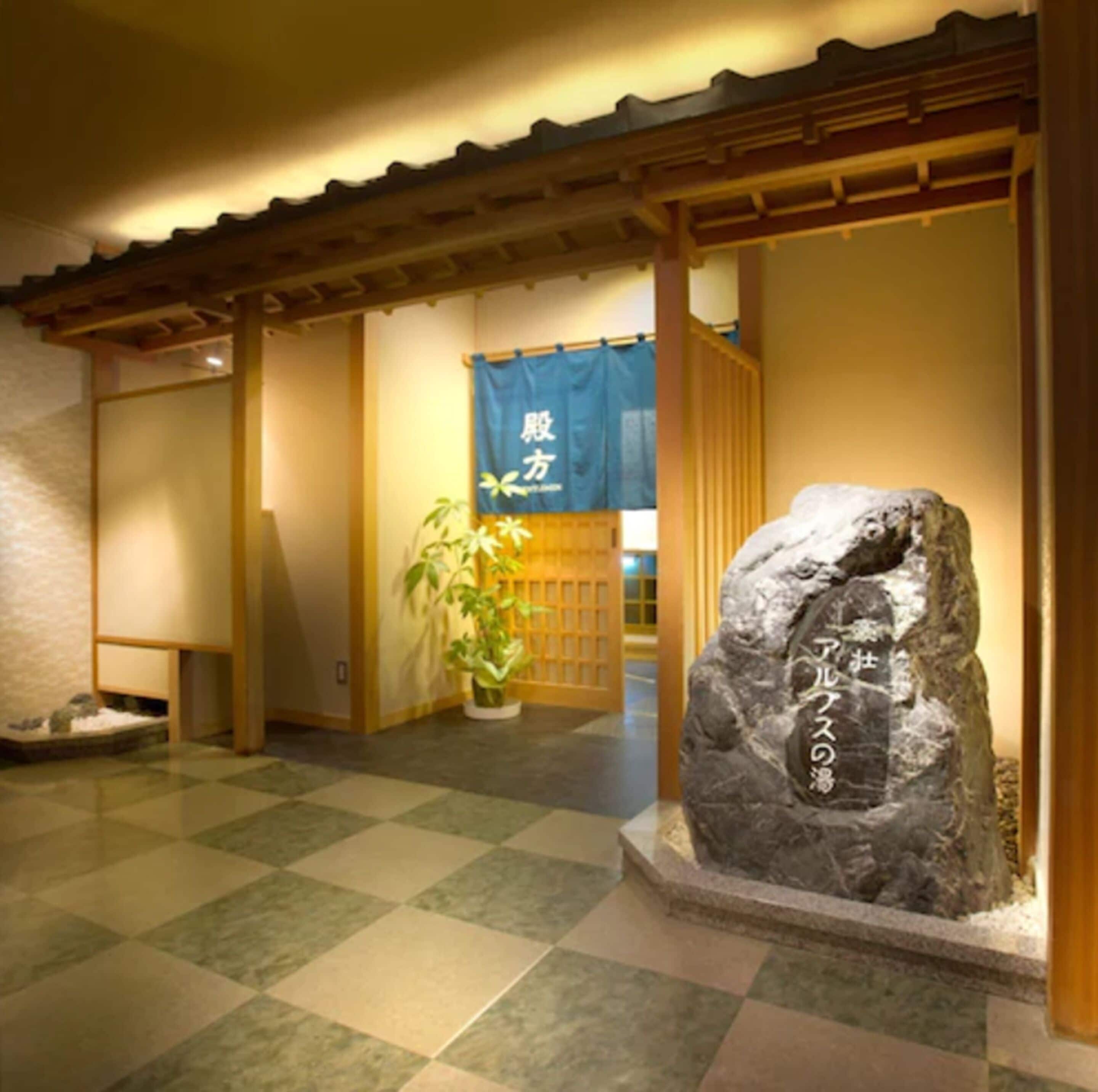 A traditional Japanese interior with tatami flooring, a rock with Japanese calligraphy, and a blue hanging banner.