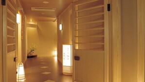 A hallway with wooden doors, a staircase, and a potted plant. - Wakakusa no Yado Maruei Ryokan (Fujikawaguchiko)