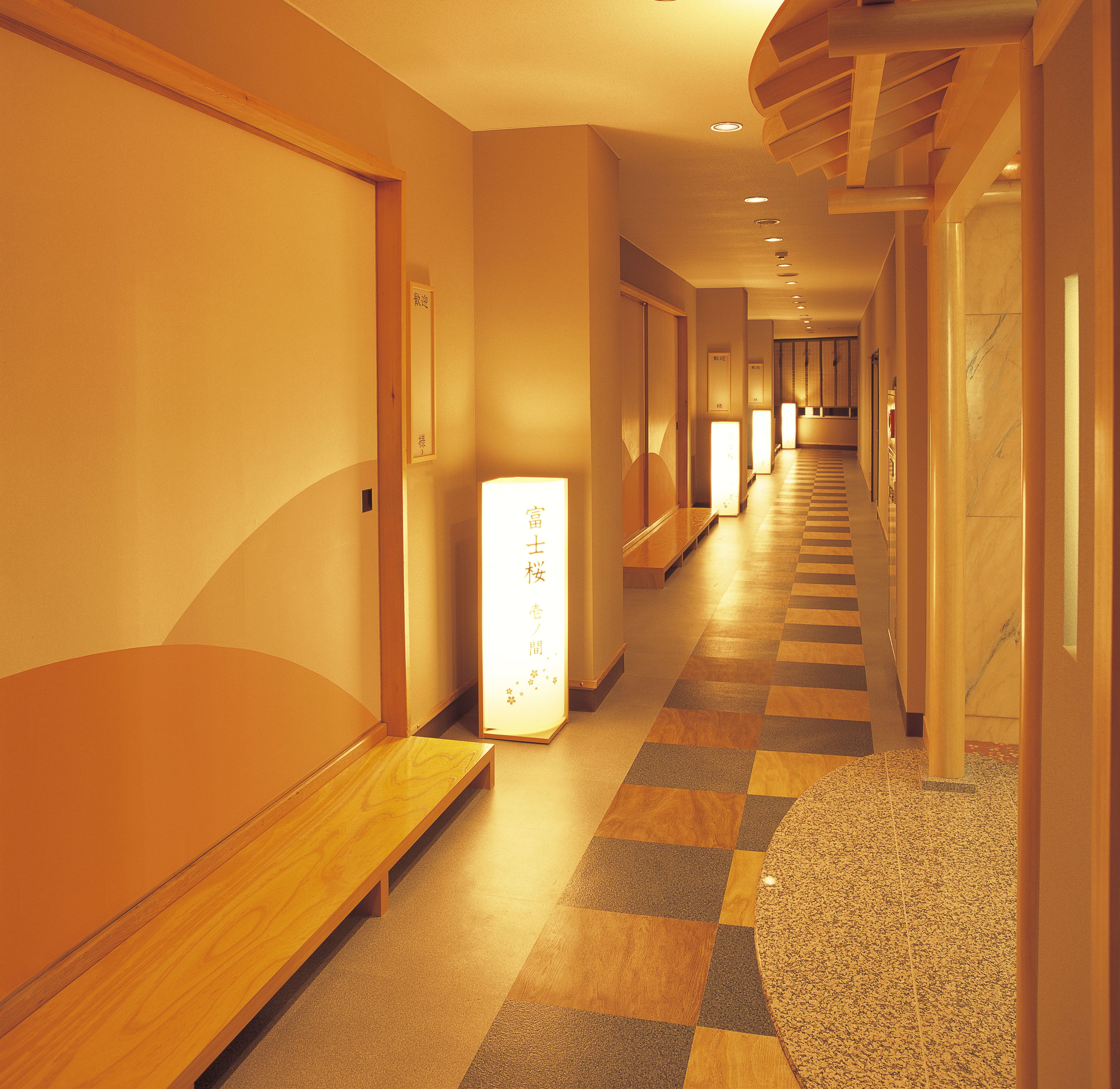 Un pasillo de hotel con bancos de madera, piso a cuadros y un mostrador de recepción al final.